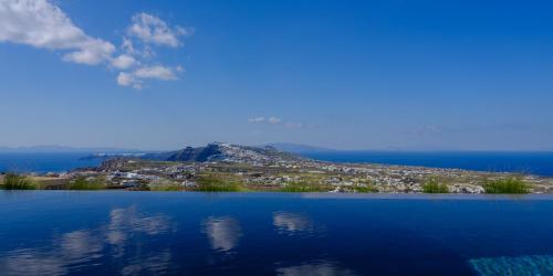 a view from a boat of the ocean with mountains at Apikia Santorini in Pyrgos
