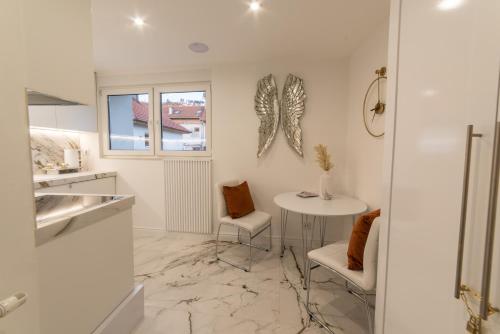 une cuisine blanche avec une table, des chaises et un comptoir dans l'établissement White House Sarajevo, à Sarajevo