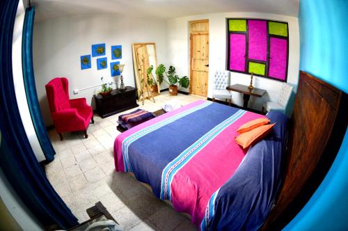 1 dormitorio con 1 cama grande y 1 silla roja en Vivir Bonito Hostal en Morelia