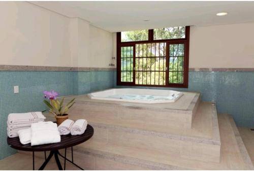 La salle de bains est pourvue d'une baignoire et d'une table avec des serviettes. dans l'établissement SUÍTE EM PEDRA AZUL - Condomínio VISTA AZUL, à Domingos Martins