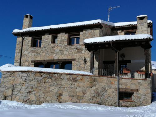 una casa de piedra con nieve encima en Casa Rural El Alcarcel, en Santo Domingo de Pirón