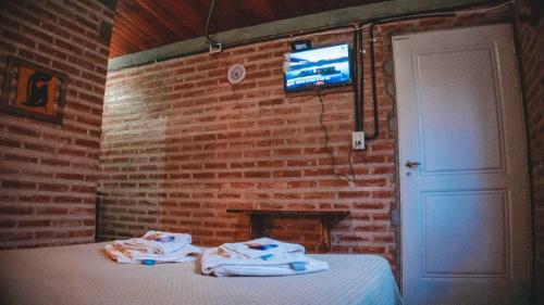 Habitación con cama y pared de ladrillo en Hotel alamos de la puntilla en Belén