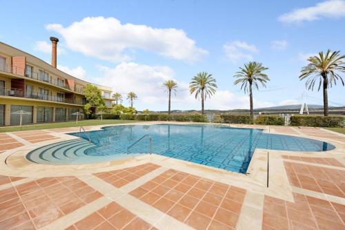 a swimming pool with palm trees and a building at BOCA DO RIO - Apartamento 109 in Estômbar