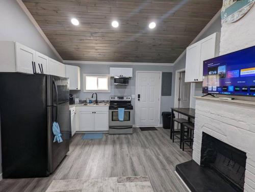 a kitchen with a black refrigerator and a fireplace at Summerlee Suite - Beautiful Remodeled Farmhouse in Oak Hill