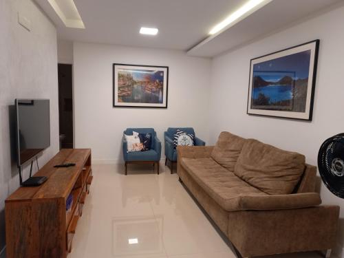 a living room with a couch and a tv at Apê da Fla in Arraial do Cabo