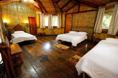 a bedroom with two beds and a wooden ceiling at Hosteria Flor de Canela in Puyo