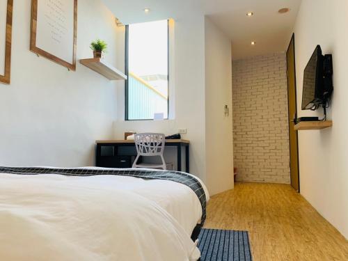 a bedroom with a bed and a desk and a window at H suite Go in Changhua City