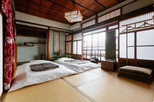 1 dormitorio con 2 camas en una habitación con ventanas en ゲストハウス君彩家 kimidoriya en Osaka