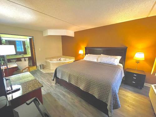 a bedroom with a bed and a bathroom with a tub at Eureka Springs Heritage Motel in Eureka Springs