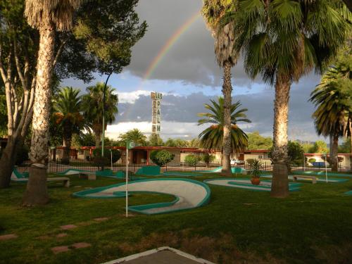 a rainbow over a golf course with palm trees at Hotel Las Palmas Midway Inn in Matehuala