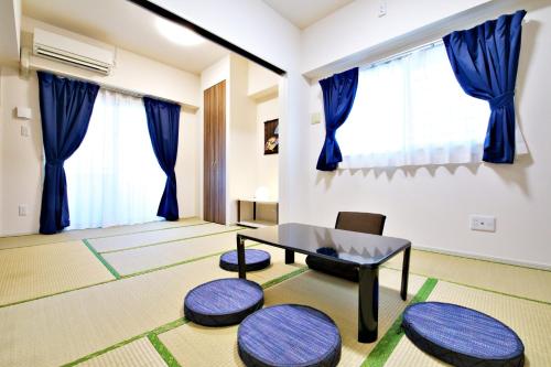 een woonkamer met blauwe gordijnen en een tafel en stoelen bij はなハウス 4F in Ginowan