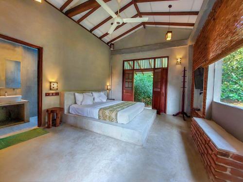a bedroom with a bed and a large window at SAYON RIVER COTTAGE & ECO GARDEN in Monaragala