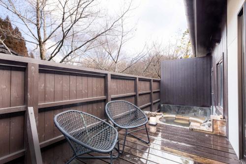 two chairs sitting on a deck with a fence at Hanare no Yado Hanagokoro in Minamioguni