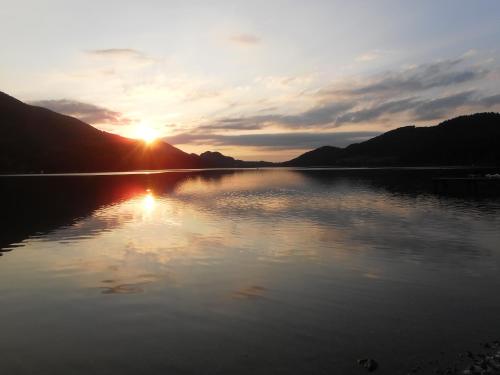 a view of a lake with the sun setting at Pension Salzburger Hof in Fuschl am See