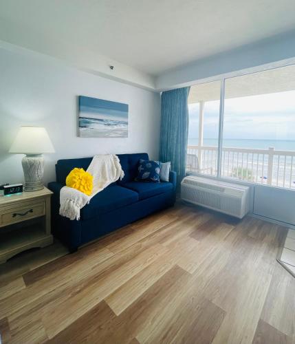 a living room with a blue couch and a large window at Daytona Beach Resort Oceanfront CondoStudio in Daytona Beach