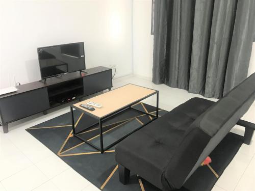 uma sala de estar com uma televisão, uma cadeira e uma mesa em OYO 90493 JL Homestay em Segamat