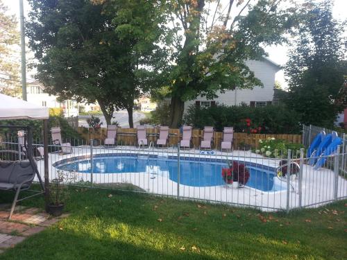 a swimming pool with a white fence around it at Gîte Le Roupillon en Beauce in Scott