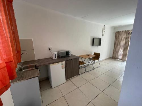 una camera con cucina completa di forno a microonde e tavolo di La Fiance Village a Polokwane
