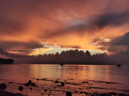 a sunset on the shore of a beach at 3-Bedroom Beach House at Glamping Dome Beach Resort in Dauin