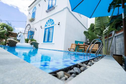 a swimming pool with a blue and white house at SANTORI Hoi An Homestay in Hoi An