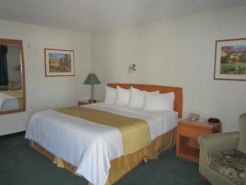a hotel room with a large bed and a chair at Ramada Merritt in Merritt
