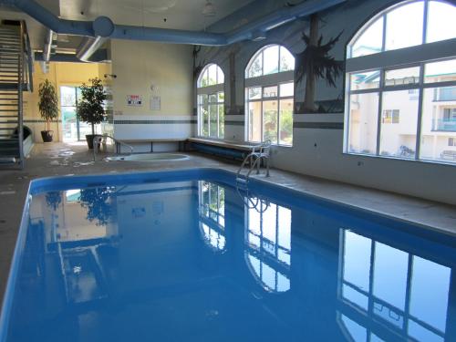 a swimming pool with blue water in a building at Ramada Merritt in Merritt
