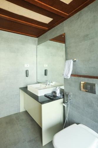 a bathroom with a white sink and a toilet at Kuruva Island Resort And Spa - By KABINI BREEZE in Mananthavady