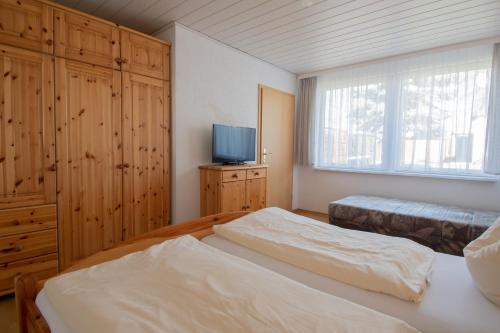 a bedroom with two beds and a television in it at Dünenhaus - Bungalow groß - zum Strand 50m in Ueckeritz