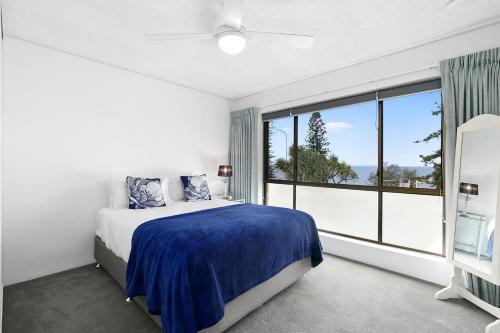 a bedroom with a bed and a large window at Beachwood at Margate Beach in Redcliffe