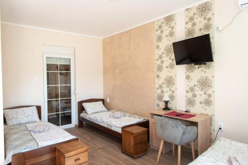 a room with two beds and a desk and a tv at Zlatni Klas in Zrenjanin