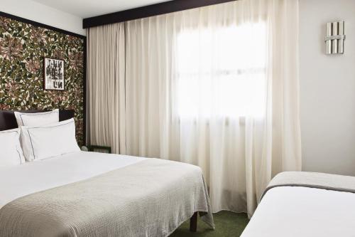 um quarto com 2 camas e uma janela em Hôtel Rosalie em Paris