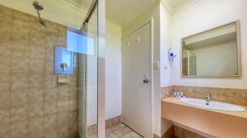 a bathroom with a shower, sink, and mirror at Bryants Motel Roma in Roma