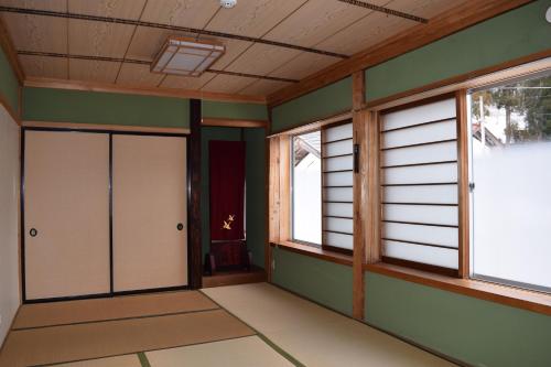 an empty room with green walls and windows at GOKAYAMA BASE in Nanto