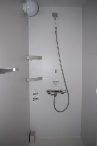 a shower with a shower head in a bathroom at GOKAYAMA BASE in Nanto