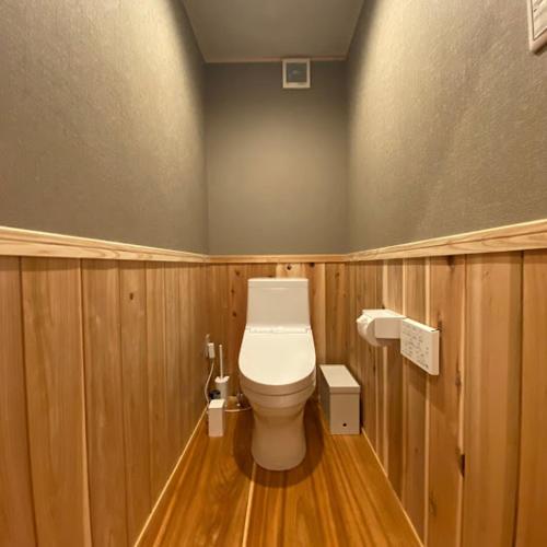 a bathroom with a toilet with wooden walls and wood floors at GOKAYAMA BASE in Nanto