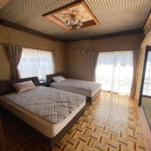a bedroom with two beds and a ceiling at GOKAYAMA BASE in Nanto