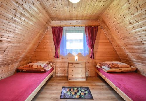 two beds in a wooden room with a window at Domki nad Soliną CZARNY KOT 509-797-777 in Solina