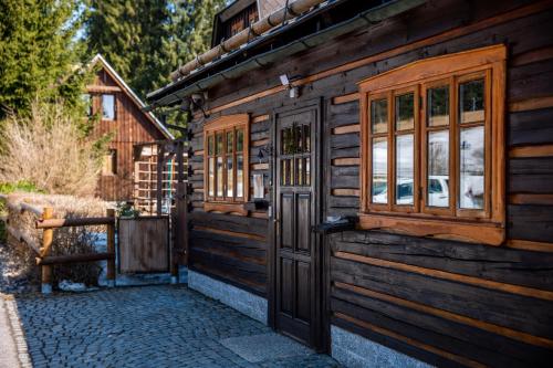 a wooden cabin with a door and a window at Penzion Koucký in Bedřichov