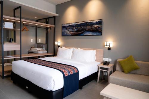 a hotel room with a large bed and a chair at Tahuna Beach Hotel and Resort in Taruna