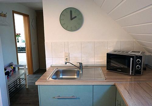 a kitchen with a sink and a clock on the wall at Ferienwohnung Burgstädt in Burgstaedt