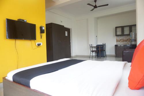a bedroom with a bed with a tv on the wall at Sorrento Homes in Pune