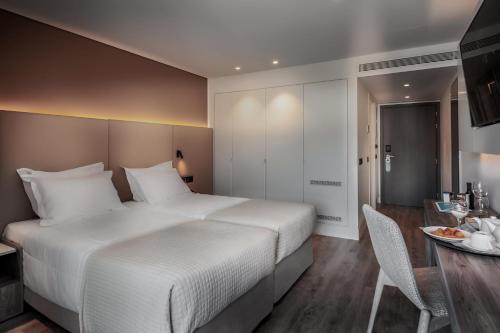 a bedroom with a large white bed and a table at Vincci EverEden in Anavissos