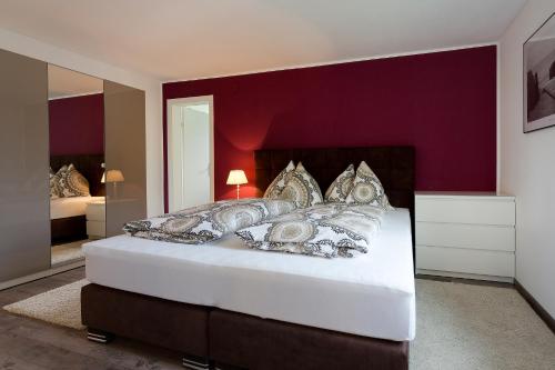 a bedroom with a white bed with a red wall at Villa Müller Turmfalke in Ossiach