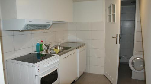 a small white kitchen with a sink and a stove at Nordanå Gård in Strö