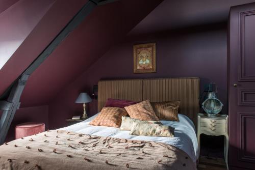 um quarto com uma cama grande e paredes roxas em La Villa Augustine em Dieppe