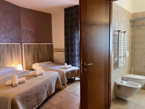 a hotel room with two beds and a toilet at Hotel Renata in Lazise
