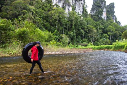 a man walking through a river with a black tire at Malulee KhaoSok Resort in Khao Sok