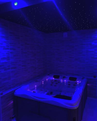 une chambre bleue avec une baignoire éclairée dans l'établissement Appartement spa gingko, N1 Valenciennes, Wifi, Netflix, à Aulnoy