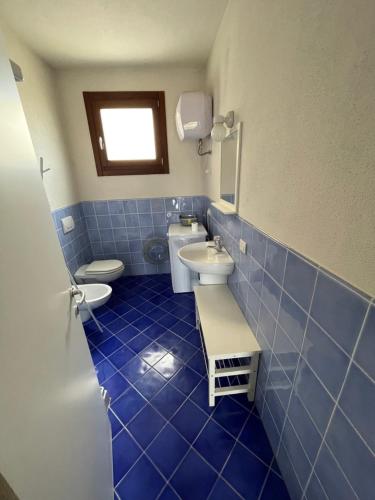 - une salle de bains carrelée de bleu avec 2 toilettes et un lavabo dans l'établissement Borgo dei Mirti, à Santa Teresa Gallura