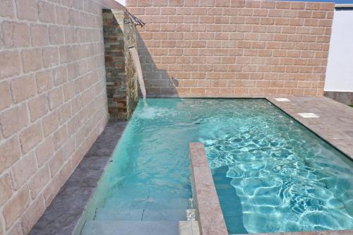 una piscina junto a una pared de ladrillo en Bungalow La Roa I, en Conil de la Frontera